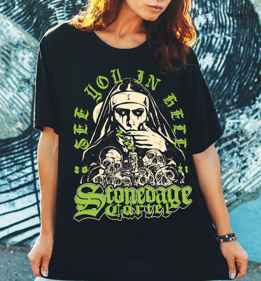 See You In Hell Unisex T-shirt, Nun Goth Smoking Weed on Pile Of Skulls Stonedage Cartel Clothing Brand.