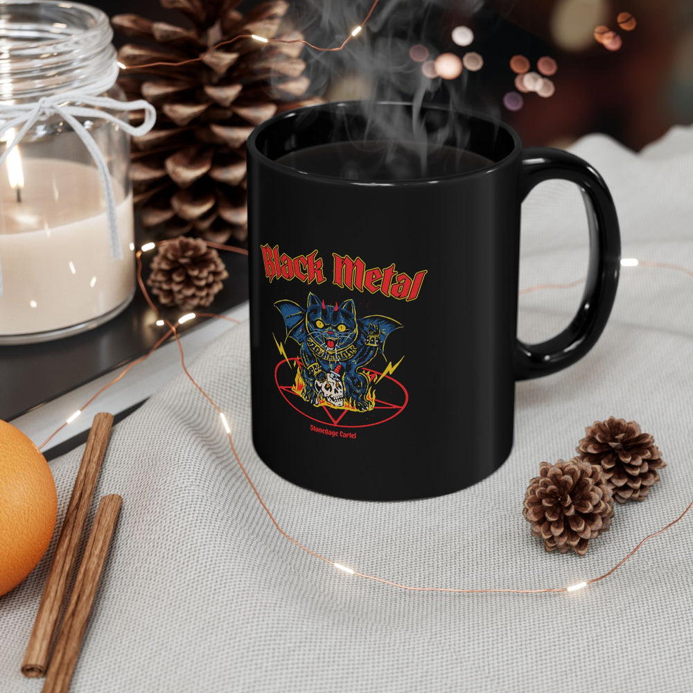 Black mug with a 'Black Metal' design featuring a cat, surrounded by decorative items on a table.