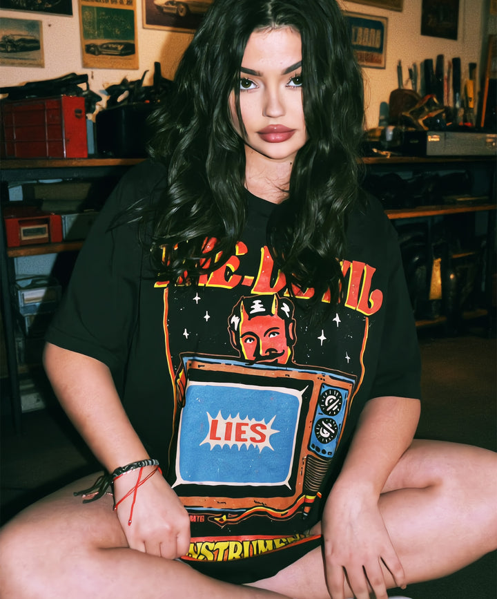 Retro Girl wearing a protest activism t-shirt with a television design and text in a room with shelves and equipment.